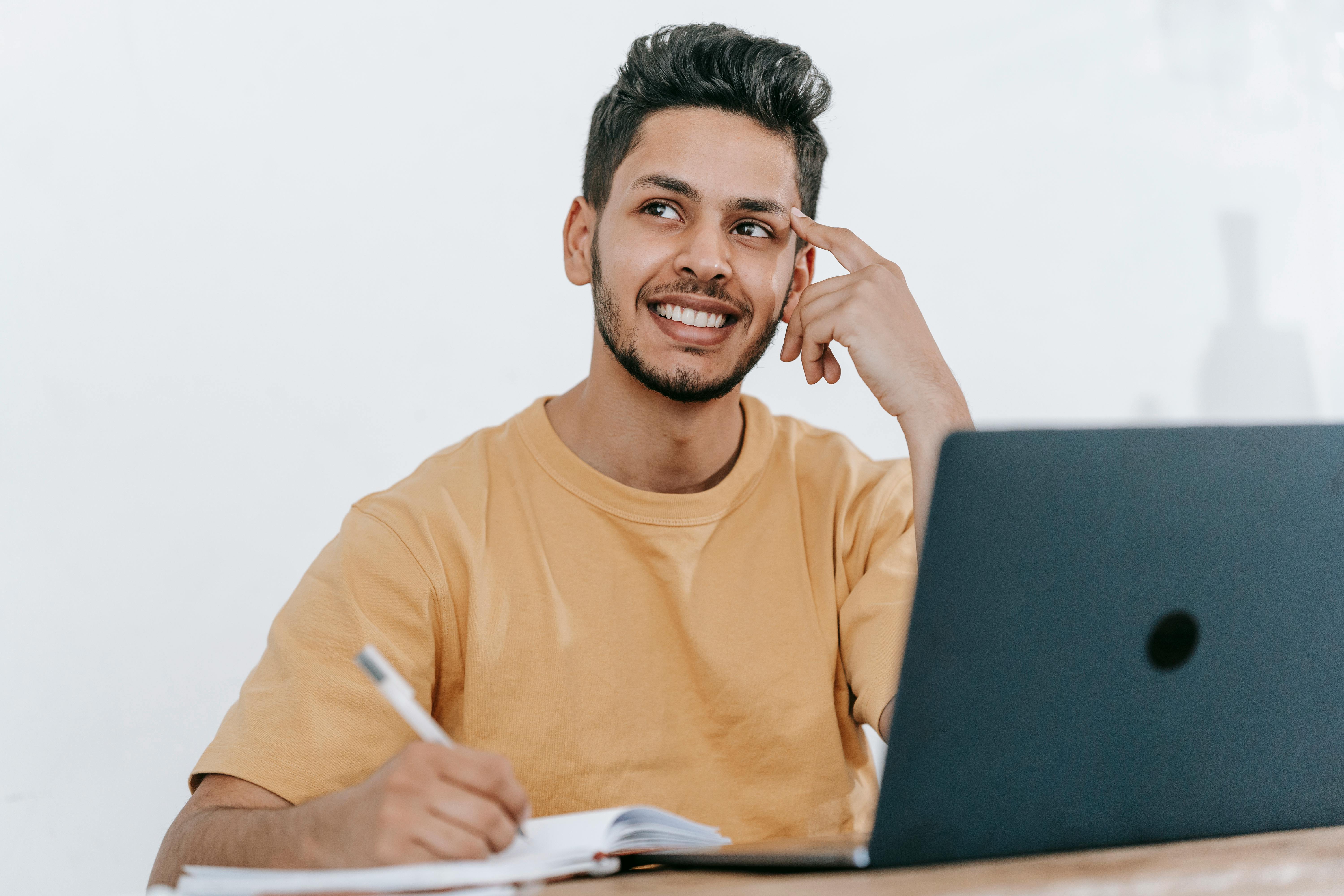 Man happy thinking with laptop and pen